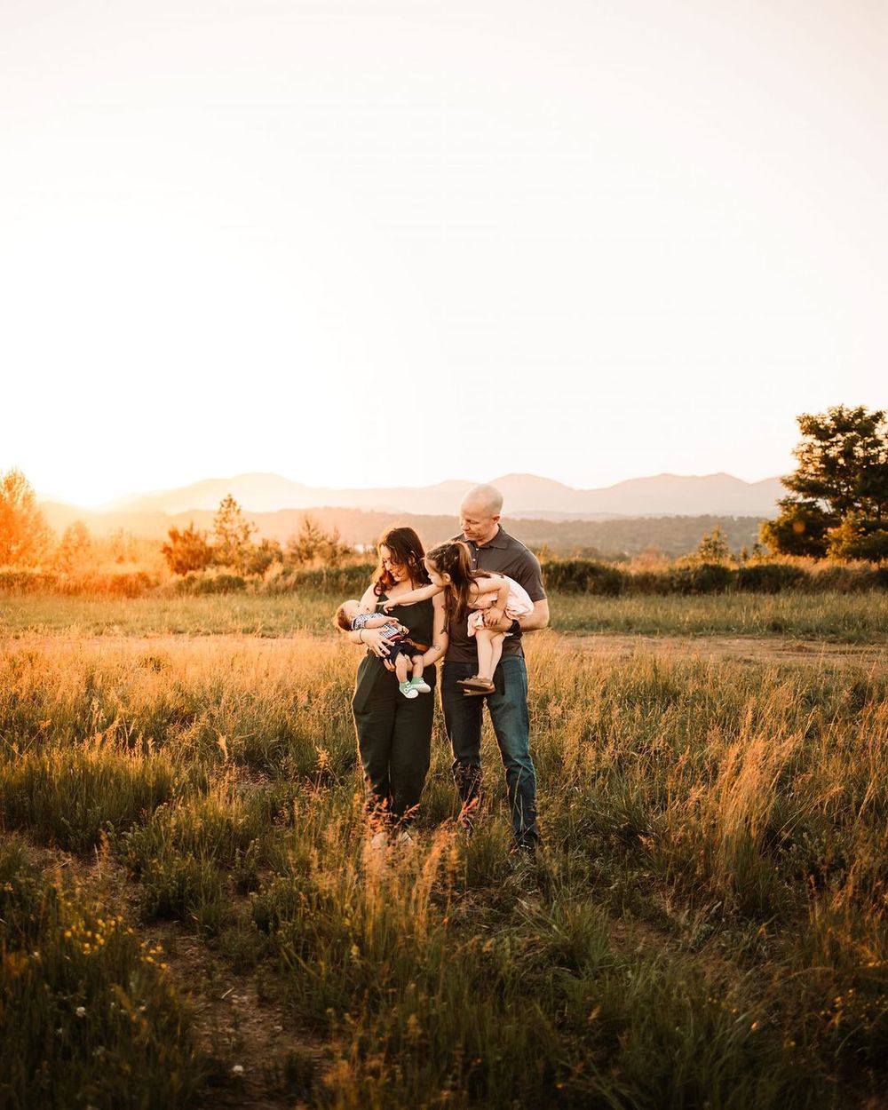Family embraces each other on sunlit mountain during golden hour in Oak Ridge, TN.
