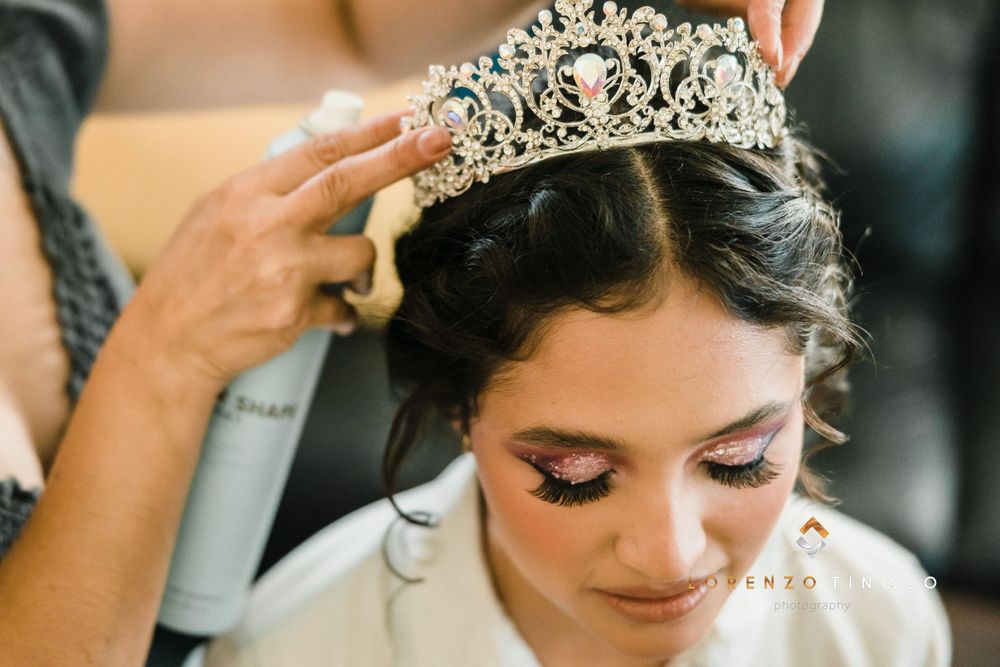 A sparkling crystal tiara being placed on styled dark hair during wedding preparations.