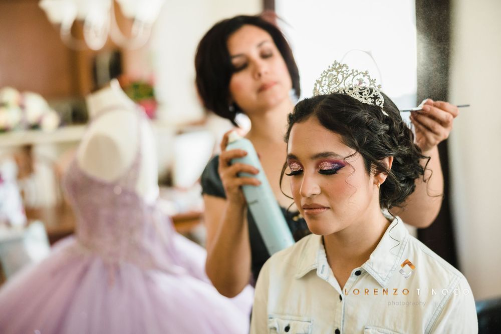 Final touches being applied during preparation with a pink gown visible in background.