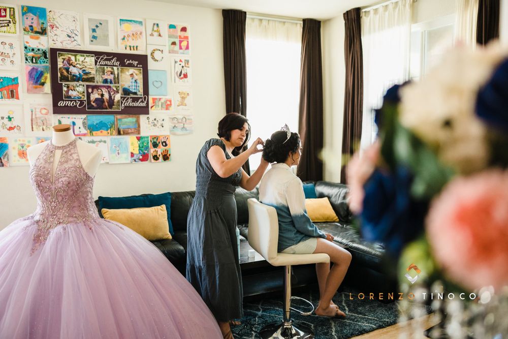 Getting ready scene with lavender quinceañera dress displayed in background of bright room.