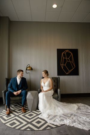 Sioux City, Iowa photographer. Bride and groom sitting in elegant chairs sharing a quiet moment indoors.