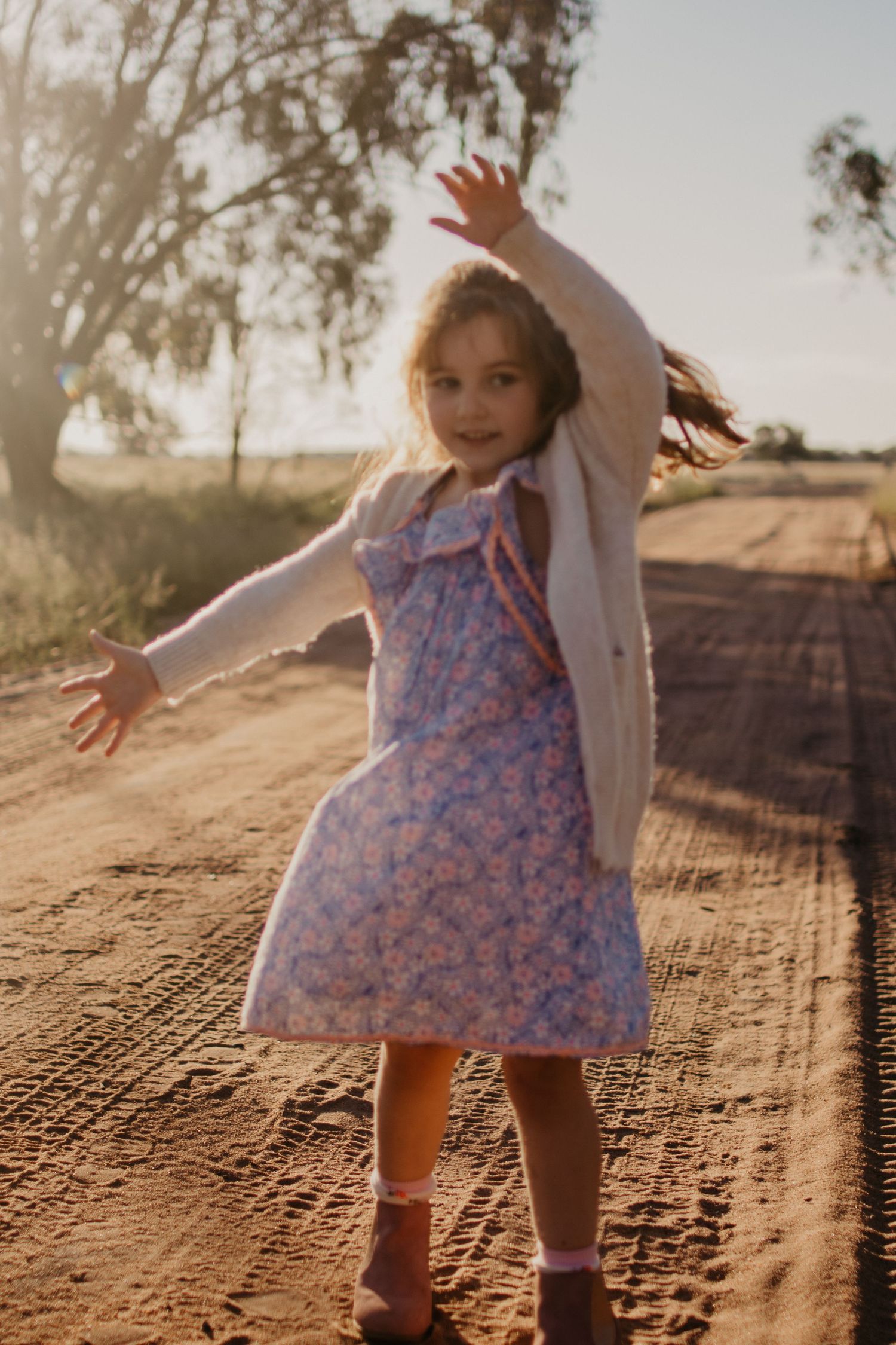 Girl twirling on a dirt road
