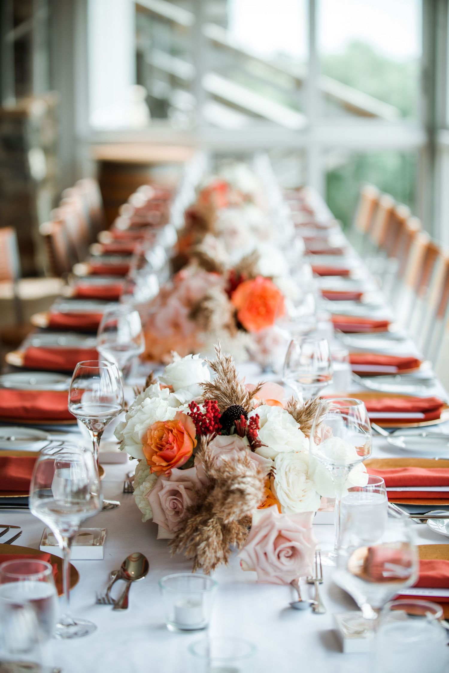 Elegant wedding reception table set with coral linens and romantic floral centerpieces.