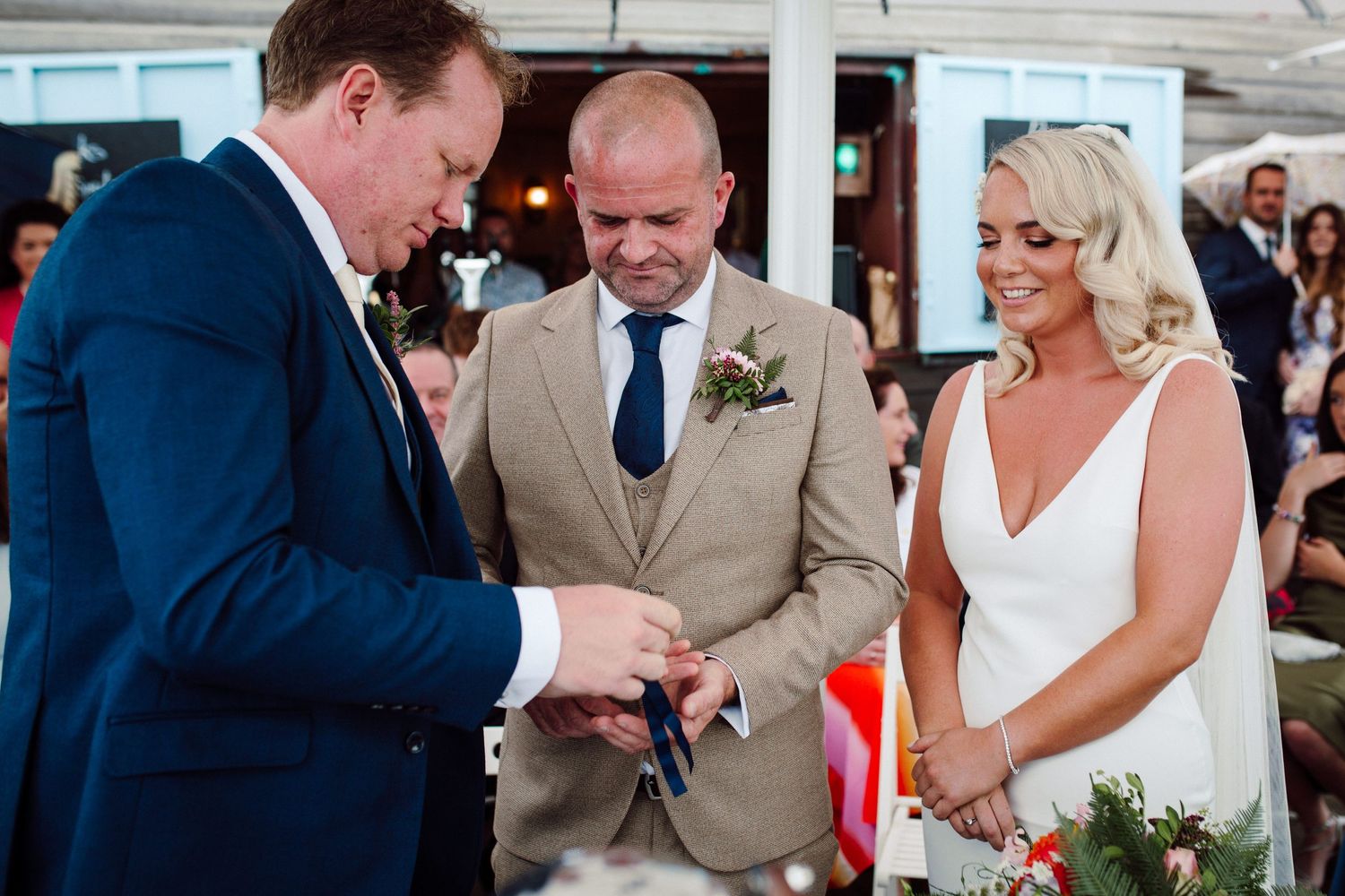 Ring exchange during outdoor wedding ceremony under white tent.