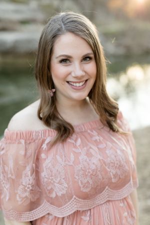 Headshot of woman in pink lace dress smiling at camera