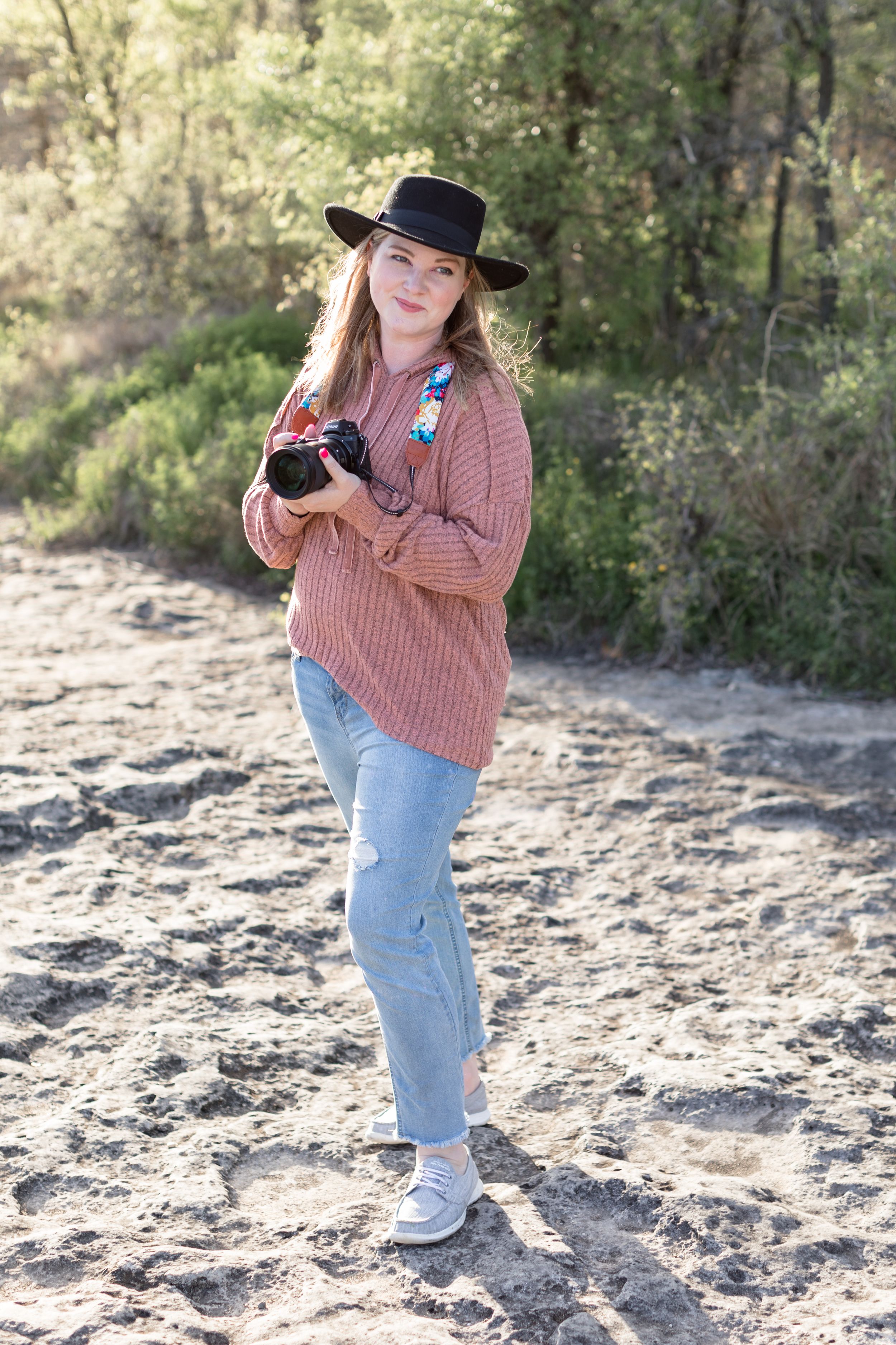Woman smiling off holding camera on rocks in Austin, TX