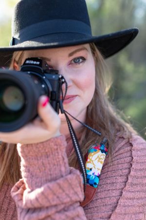 Close up of woman in hat with camera up to one eye