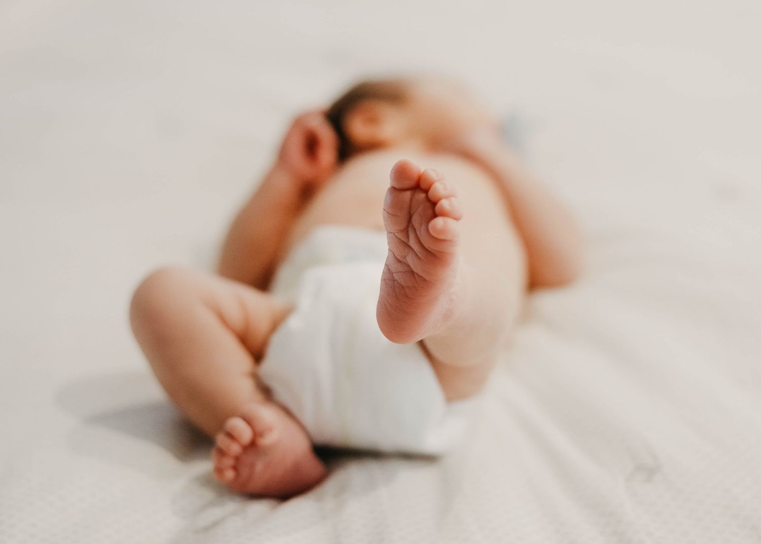 Tucson newborn photographer captures a soft close-up of tiny baby feet during an in-home lifestyle session.