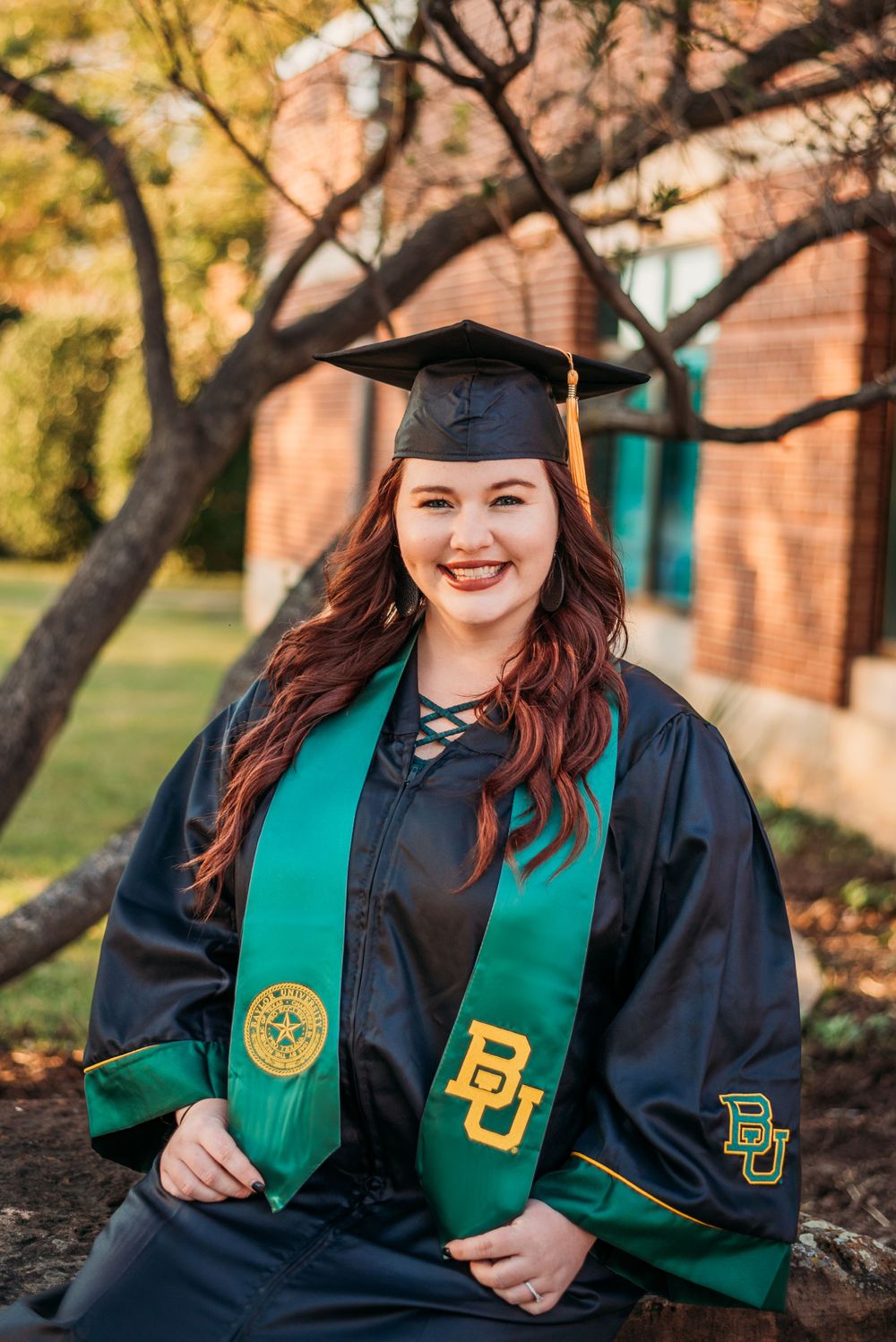 Baylor university college Graduate sitting down smiling in graduation robe in Waco Texas