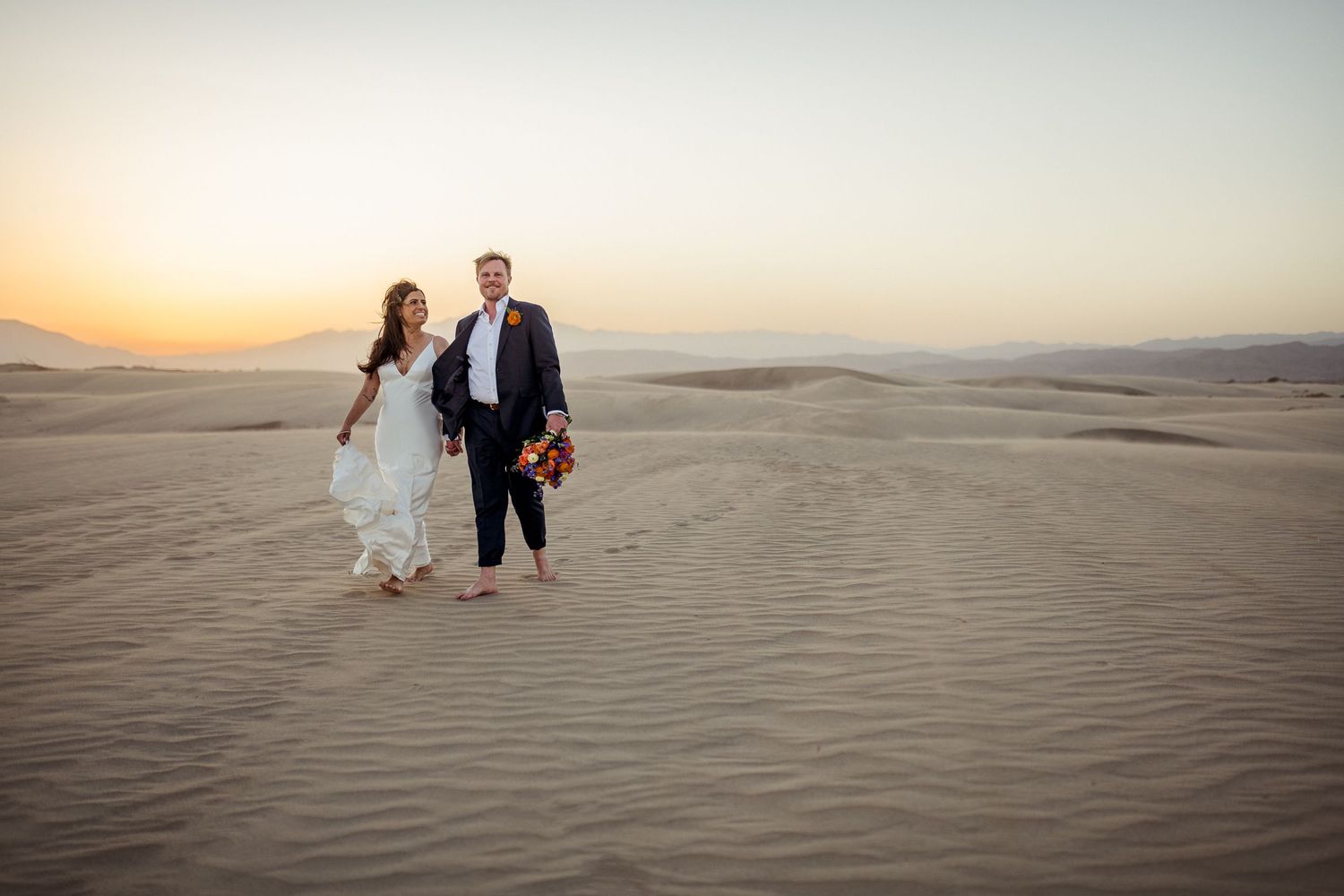 A romantic walk across desert sand dunes during golden hour.