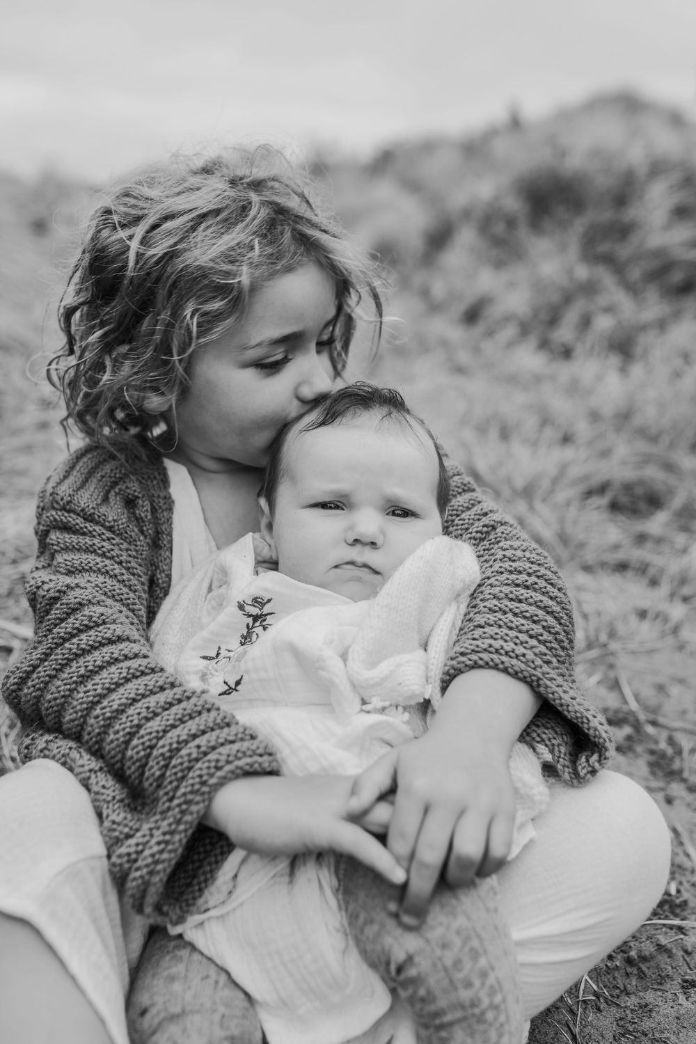 Black and white portrait of mother and baby sharing an intimate moment outdoors.