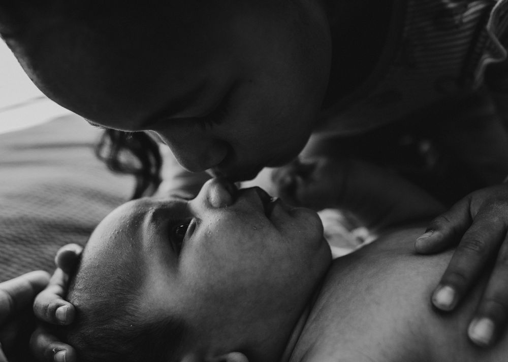 Intimate black and white portrait of parent and infant sharing a loving moment.