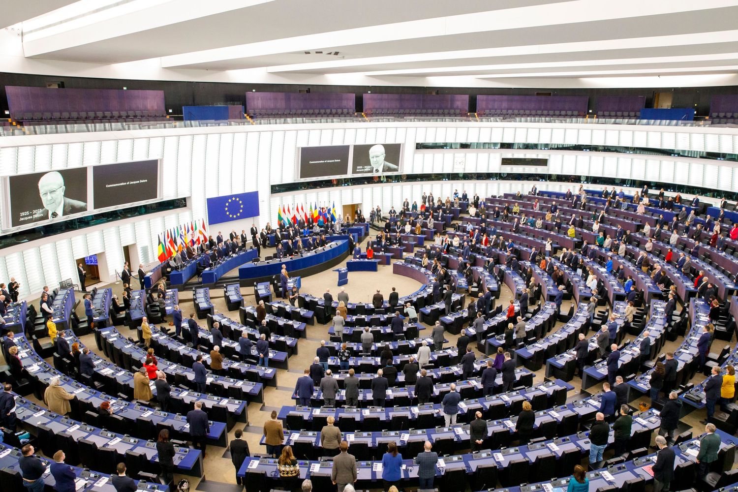 Wide view of European Parliament assembly hall during session with curved rows of seats.