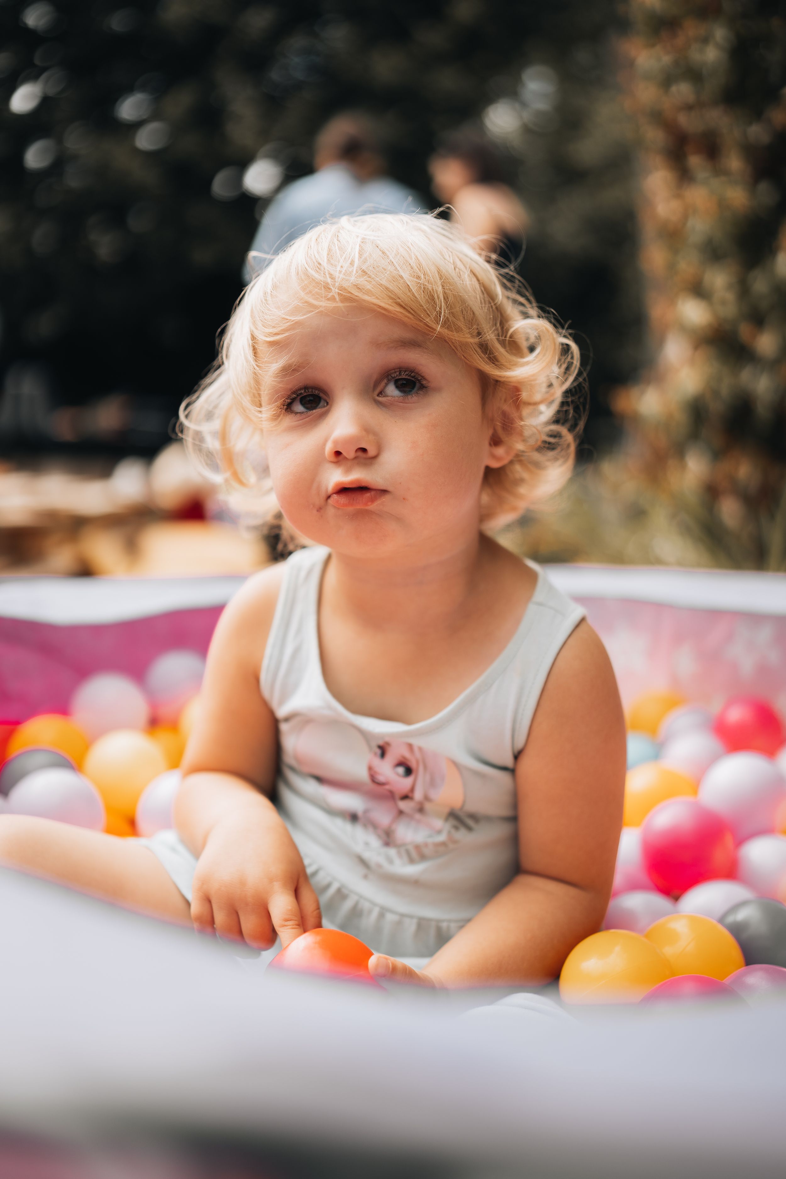 Baby playing with colorful balls on white surface at celebration.
