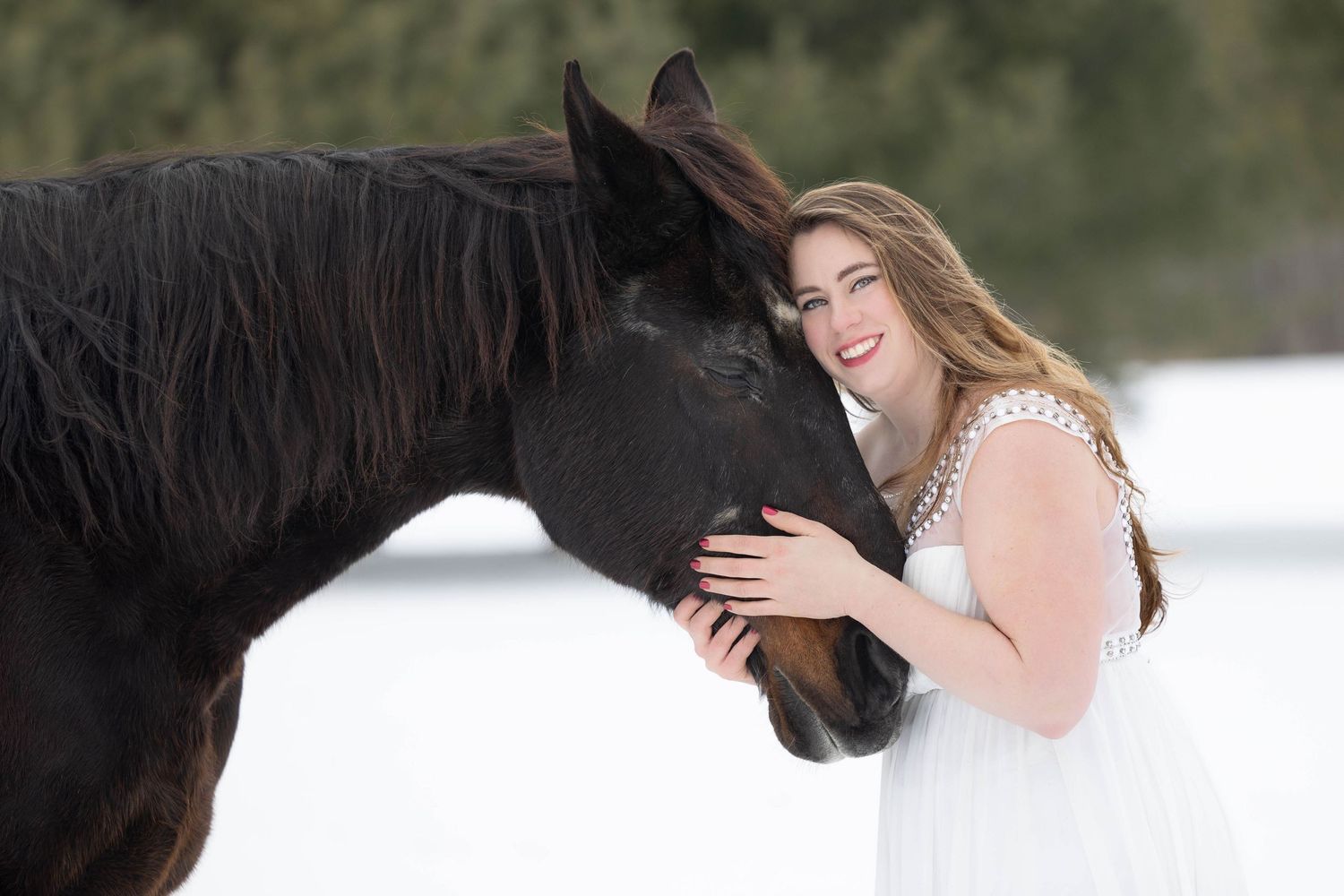 Girl in white dress with large bay horse in a winter landscape