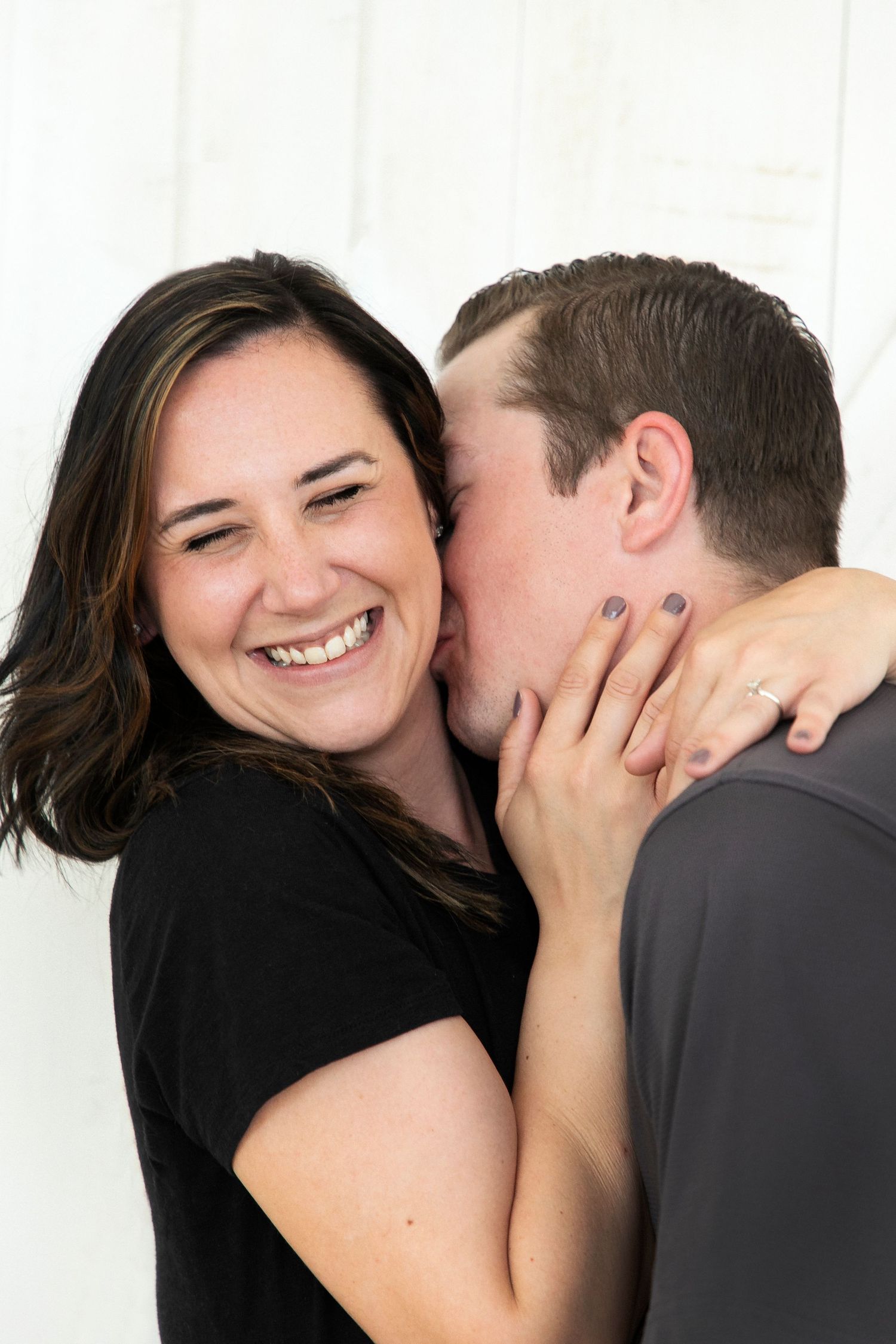 A man giving his fiance neck kisses.