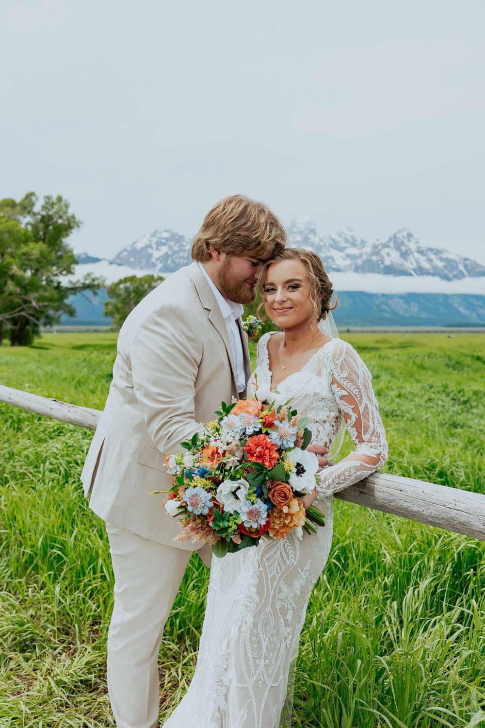 A romantic wedding photoshoot in a mountain meadow with colorful bouquet and dramatic landscape.