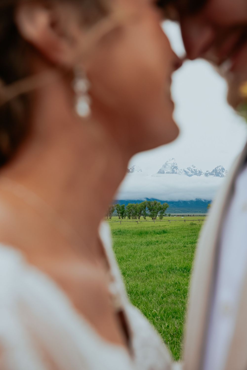 Wedding couple portraits with a scenic mountain landscape and green meadow in the background.