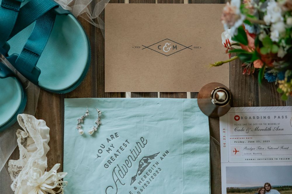 Wedding details including turquoise flip flops, invitation suite, and vintage decor on wooden surface.