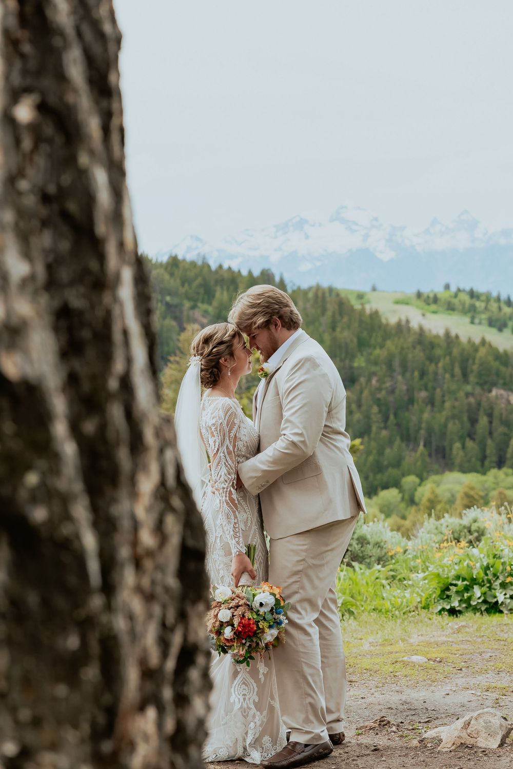 A romantic wedding moment captured against a backdrop of rolling hills and distant mountains.