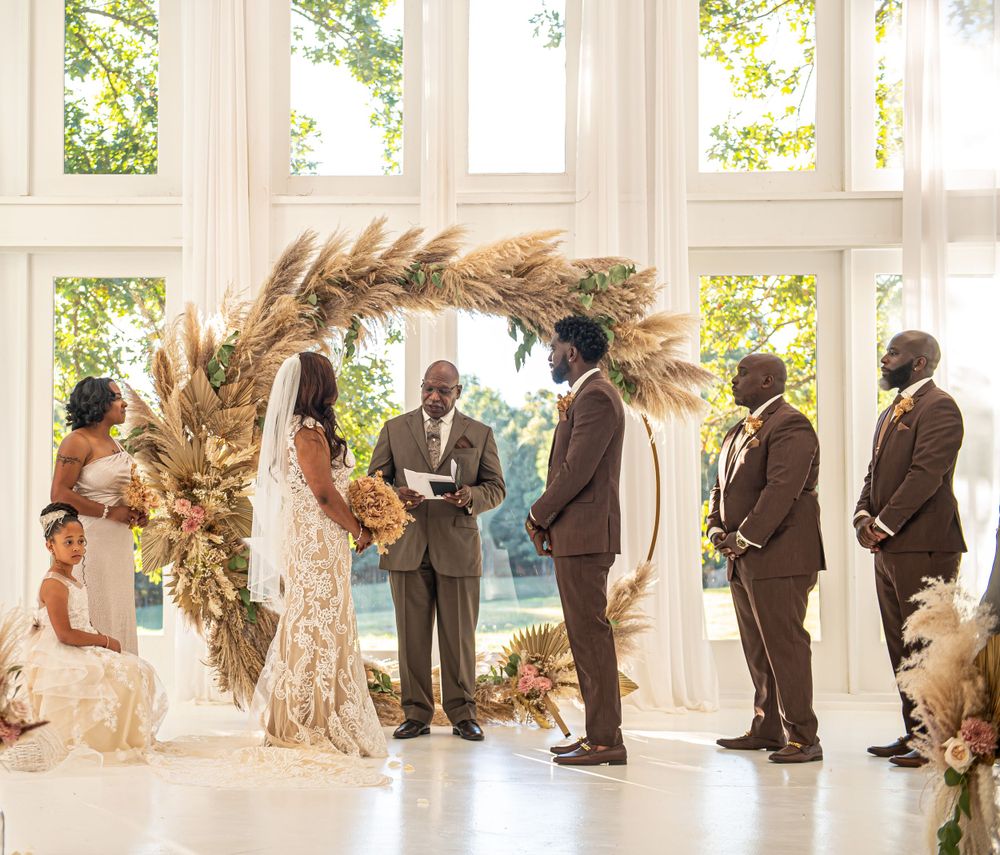 A wedding ceremony space decorated with pampas grass arch and natural light streaming through windows.