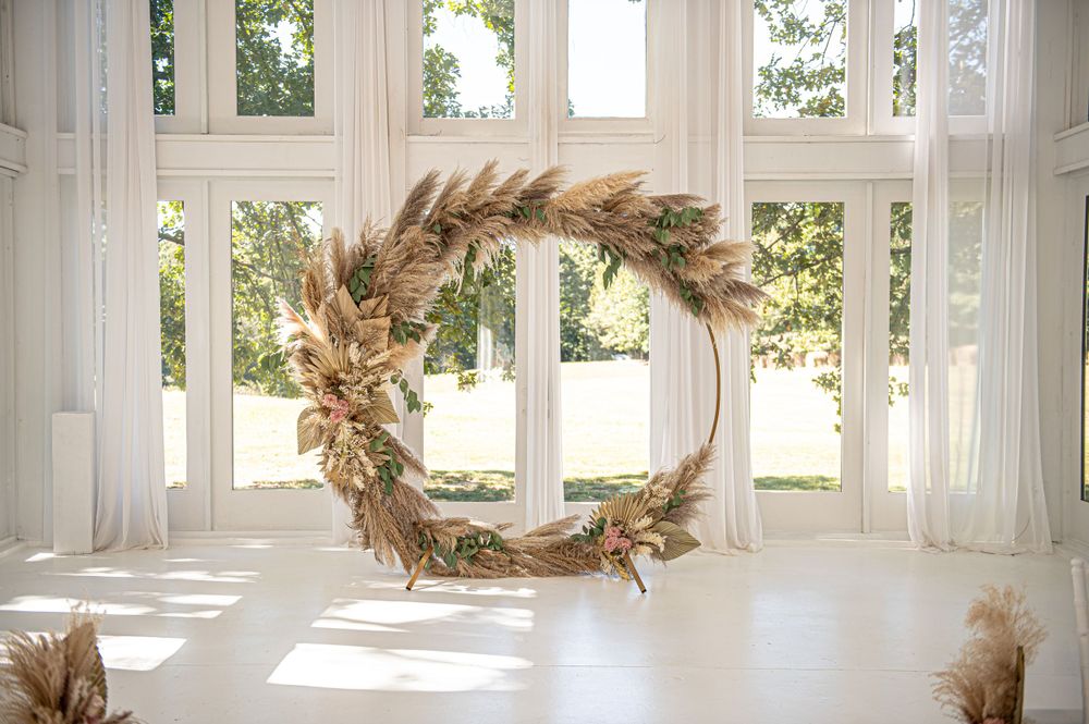 Minimalist dried floral wedding wreath hanging in a bright white sunlit room.