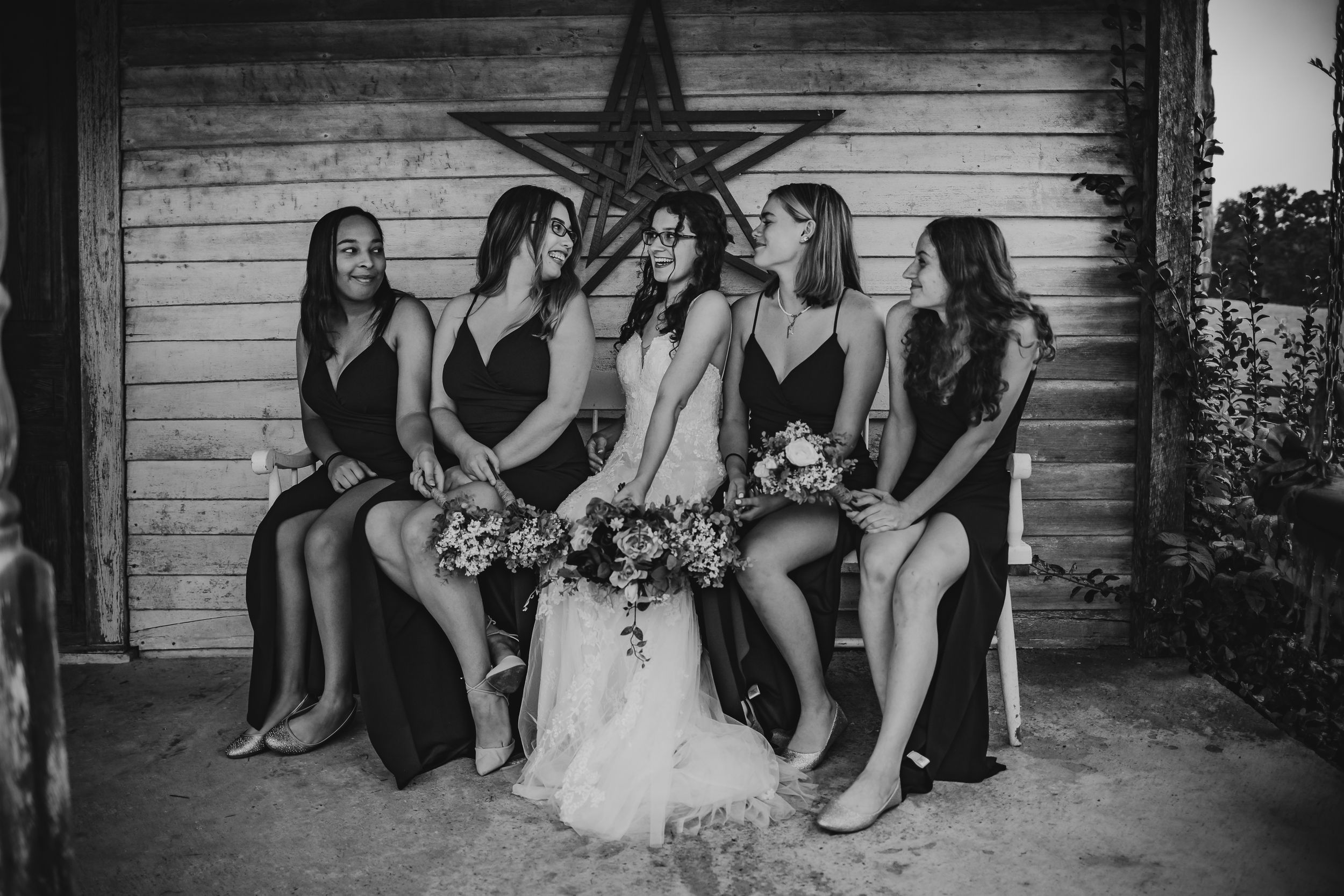 Wedding party poses for photo in front of rustic wooden wall with star decoration.
