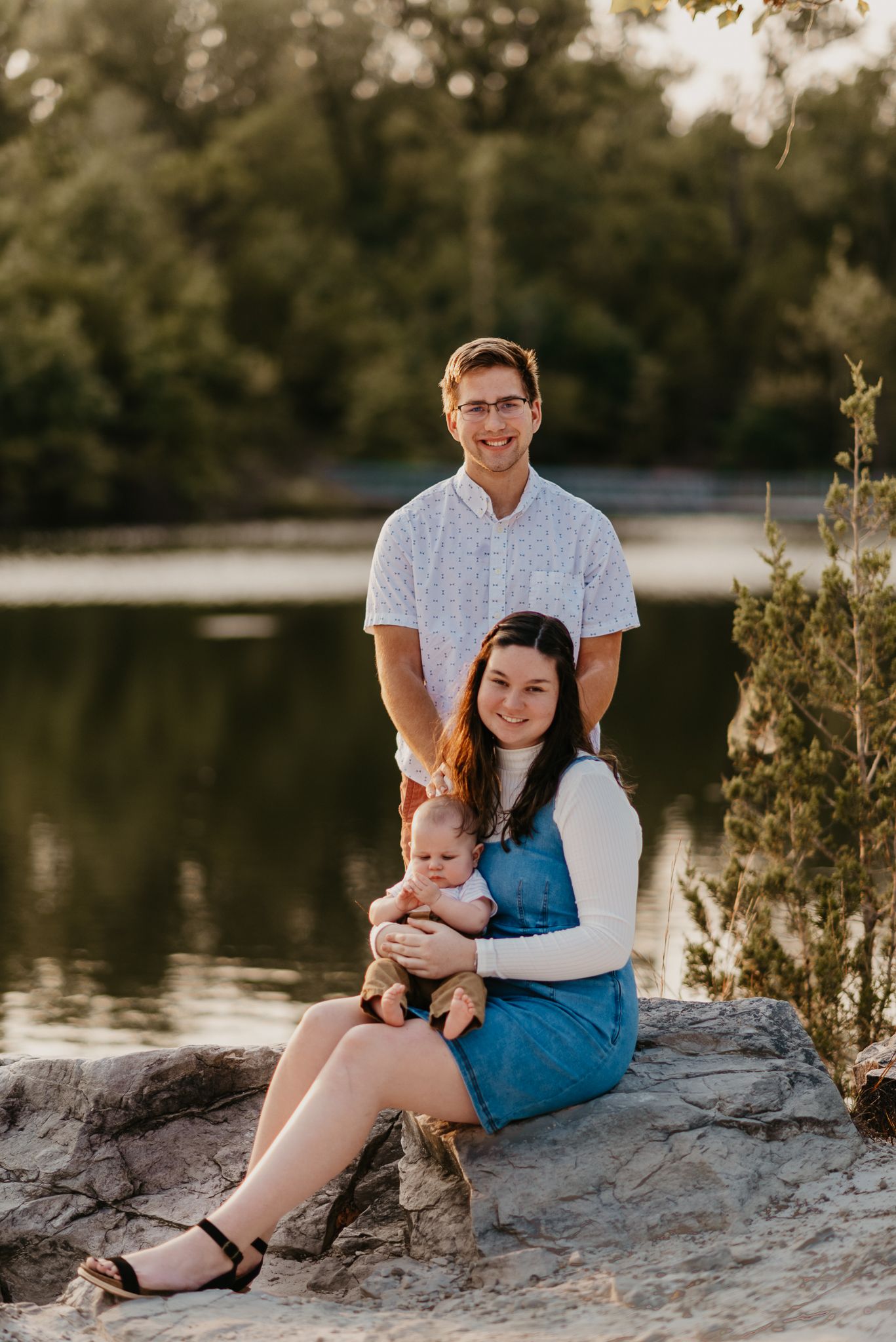 Family portrait session on rocky shoreline during sunset at a lake.