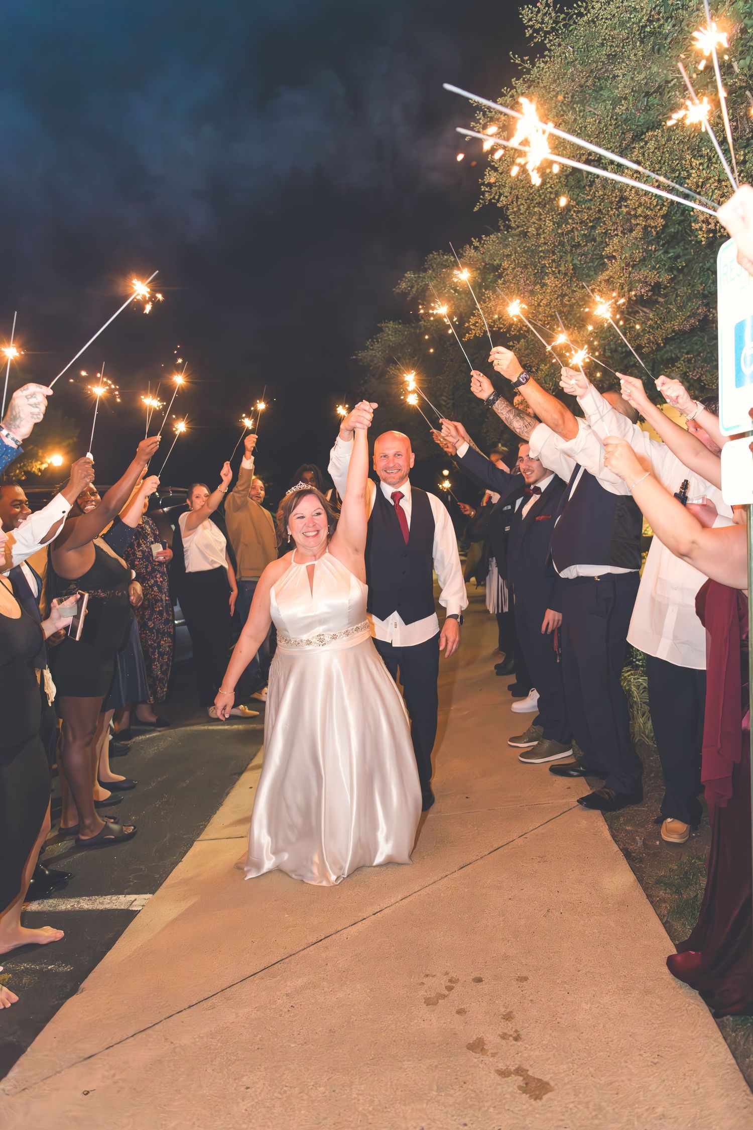 Wedding guests create a sparkler exit tunnel for the newlyweds at night.
