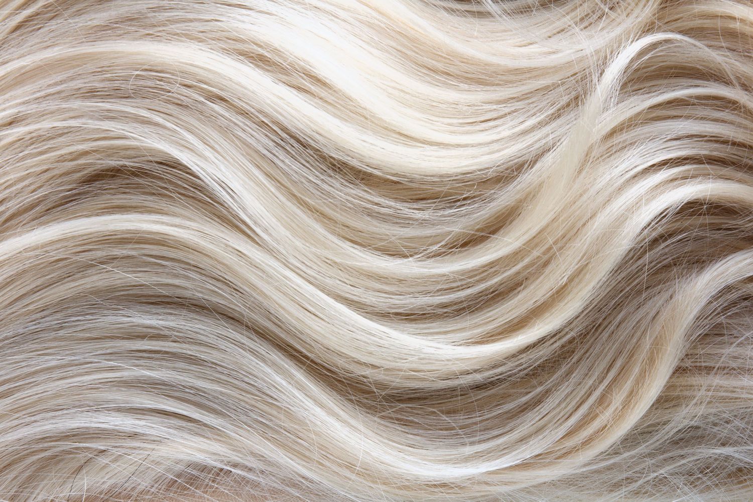 Close-up of wavy platinum blonde hair extensions with natural texture.