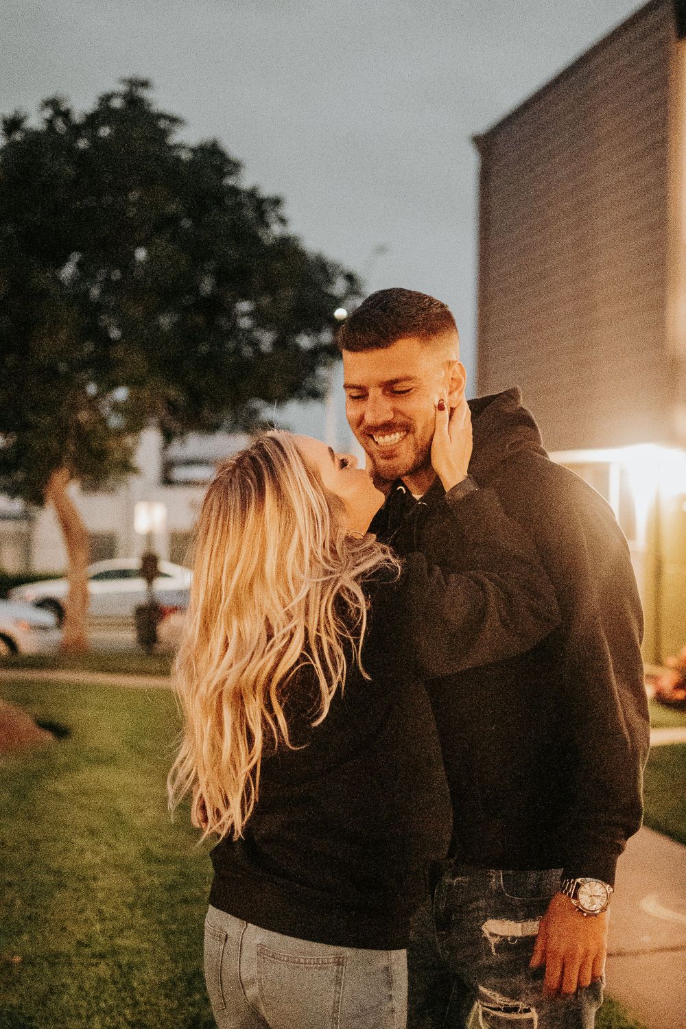 A couple shares an intimate moment laughing together at sunset.
