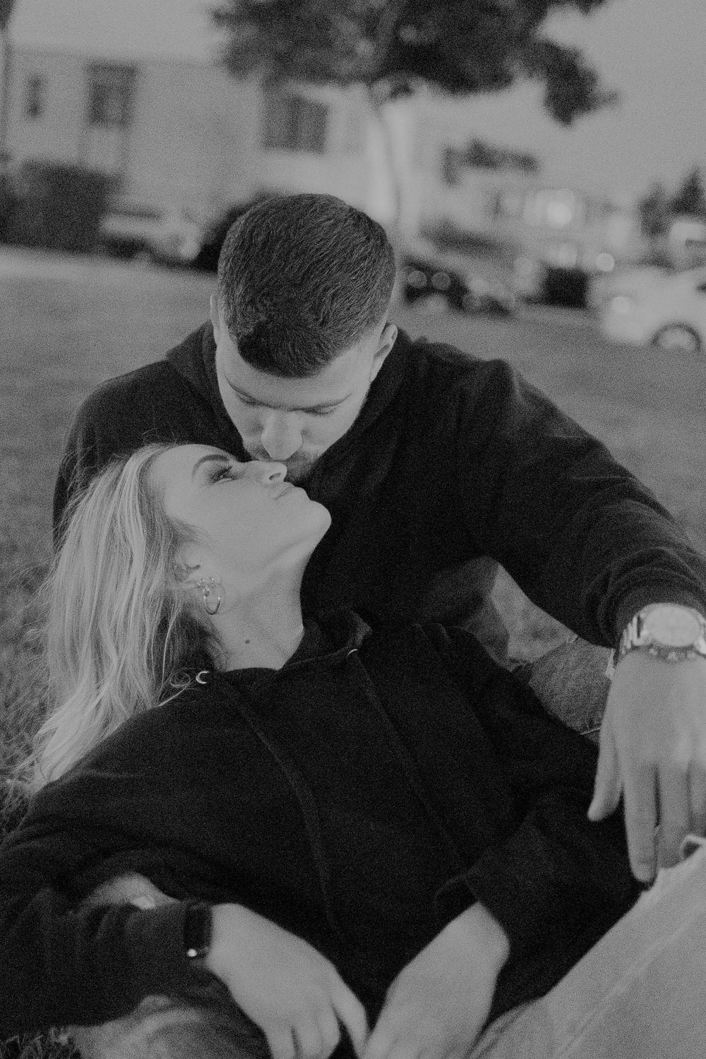 A couple shares an intimate moment on grass during sunset.