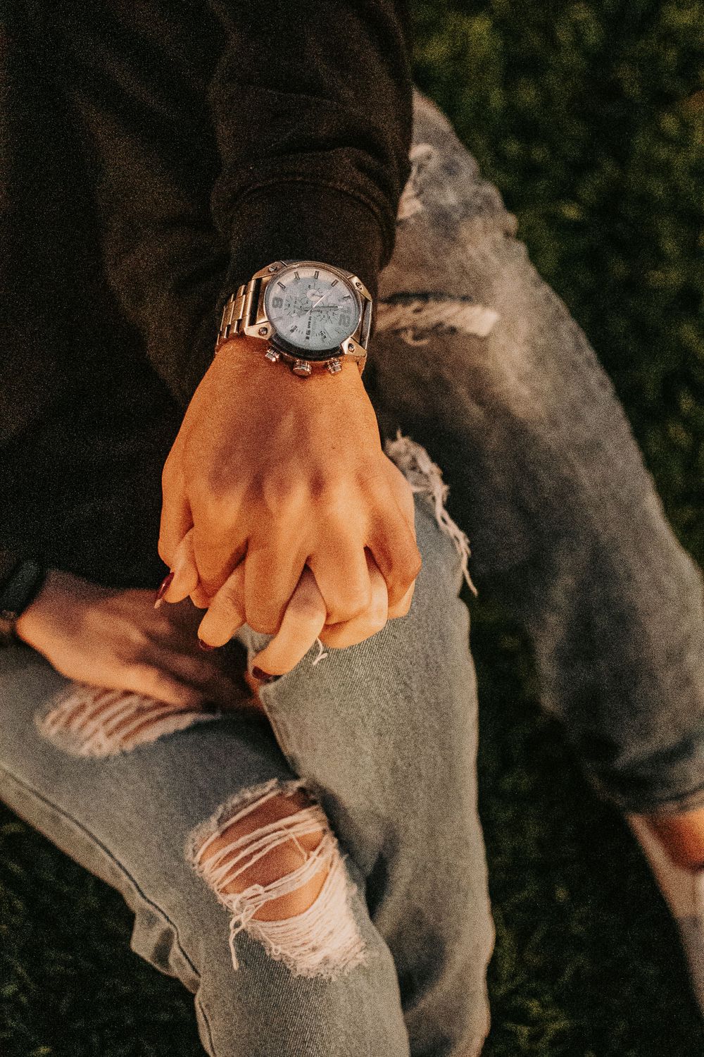 Close-up shot of hands with wristwatch against distressed denim background.