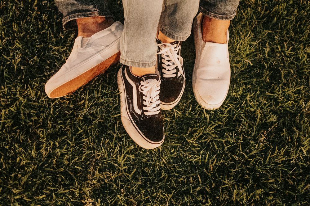 Shoes and legs of couple sitting together on grass in casual wear.