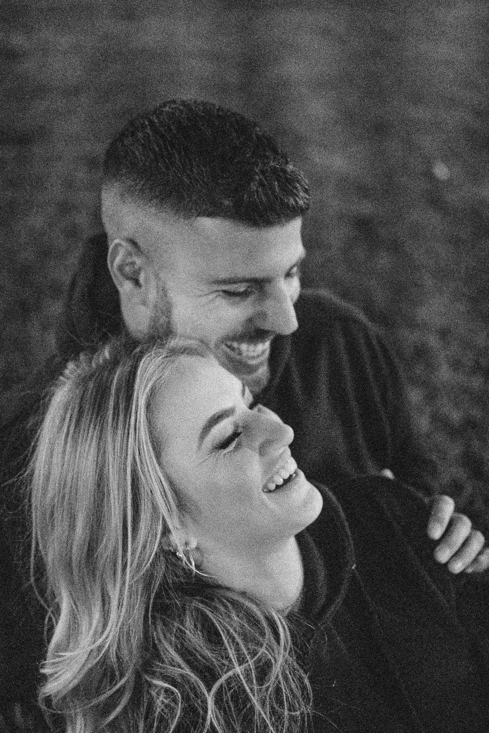 Intimate black and white portrait of couple sharing joyful moment outdoors.