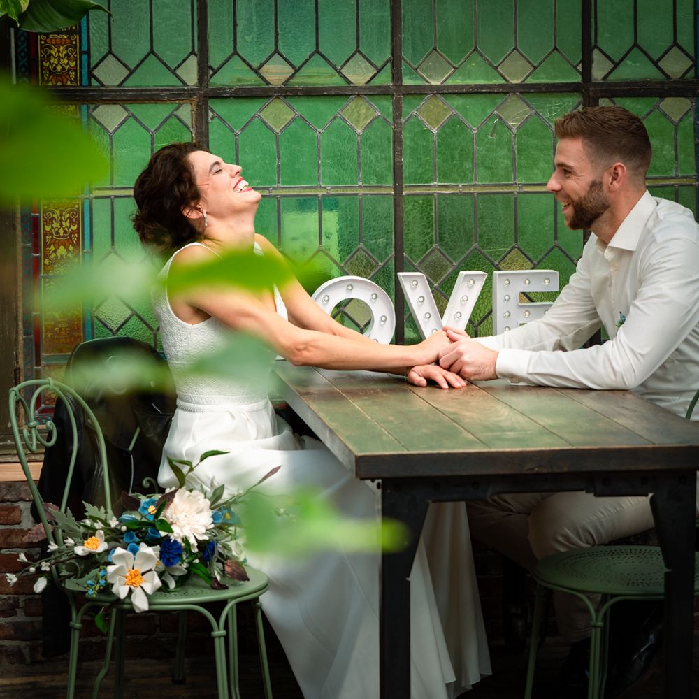 Lachend bruidspaar bij het LOVE decor in de Foodhall – bruidsfotografie Arnhem