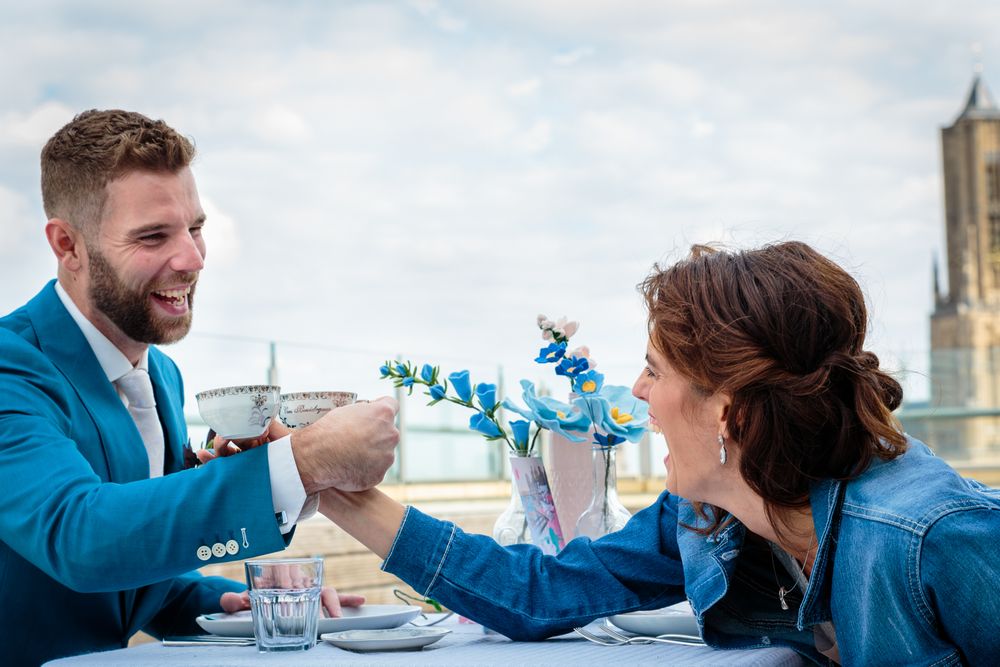 Lachend bruidspaar proost aan tafel op het dakterras van Rozet – trouwfotografie Arnhem
