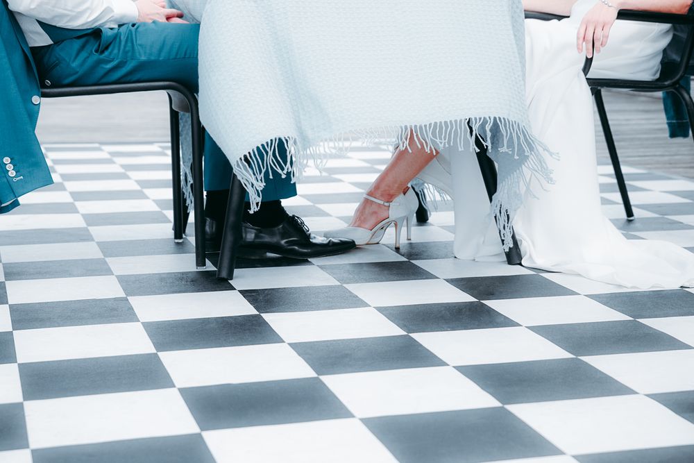 Speels detail van bruidspaar onder tafel op het dakterras van Rozet – bruidsfotografie Arnhem