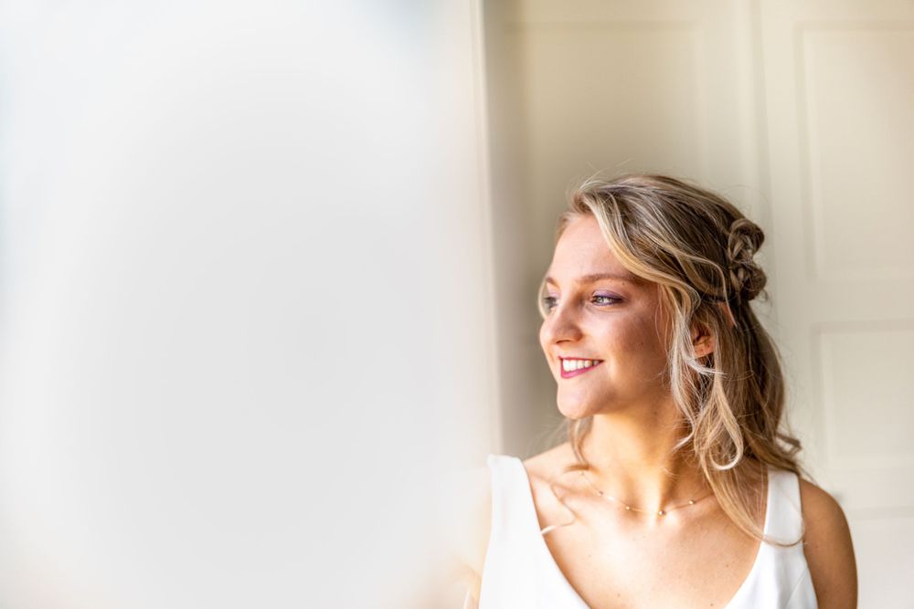 Stralende bruid bij het raam in Kasteel Spelderholt – trouwfotografie Gelderland