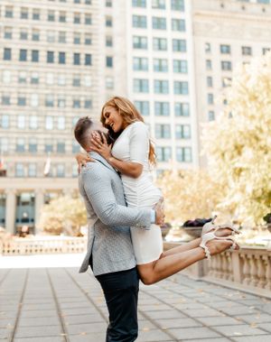 Romantic couple embracing and laughing in front of city buildings on a sunny day.