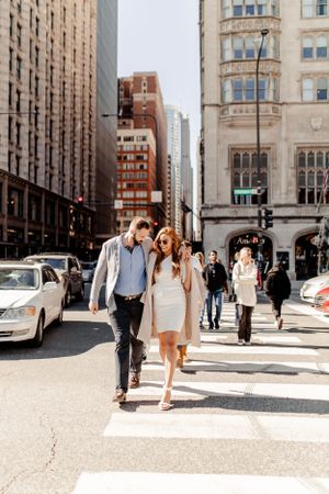 Couple walking together and smiling on a busy city street in downtown.