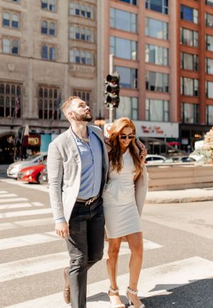 Happy couple posing playfully at an urban intersection with buildings in background.