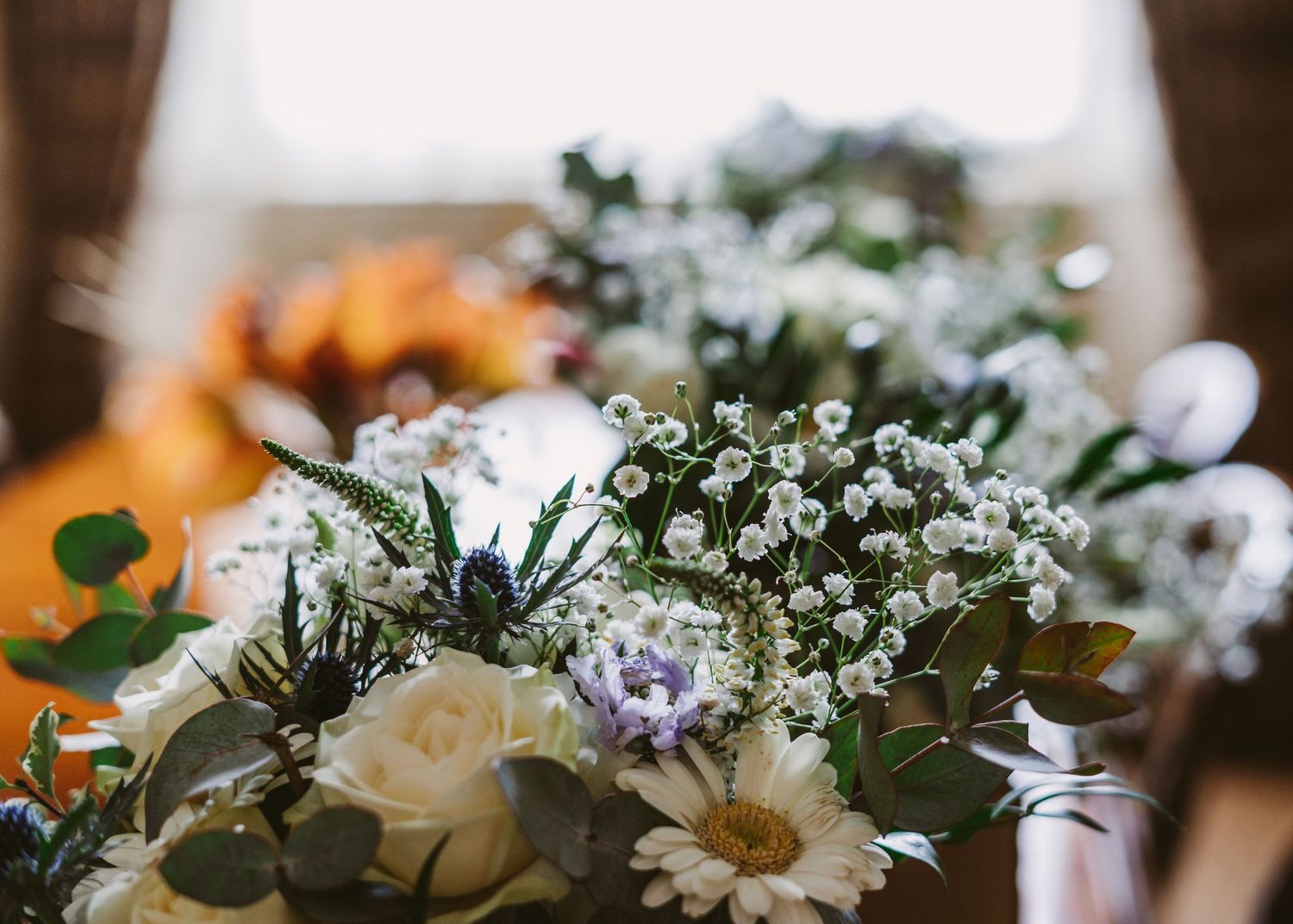 Close-up of delicate white and purple wildflower wedding bouquet arrangement.