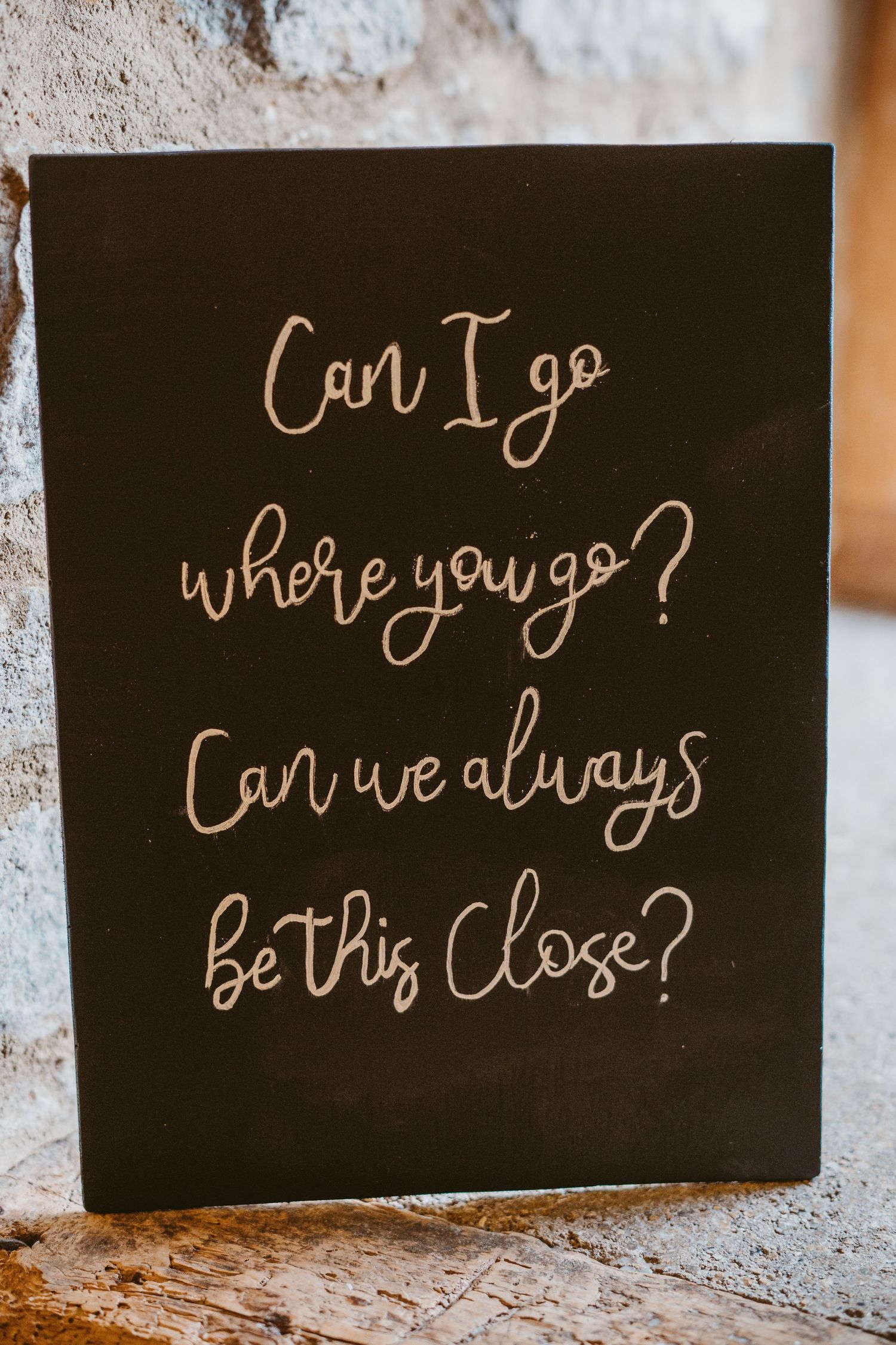 Handwritten cursive text on black board reads 'Can I go where you go? Can we always be this close?' in ivory color.