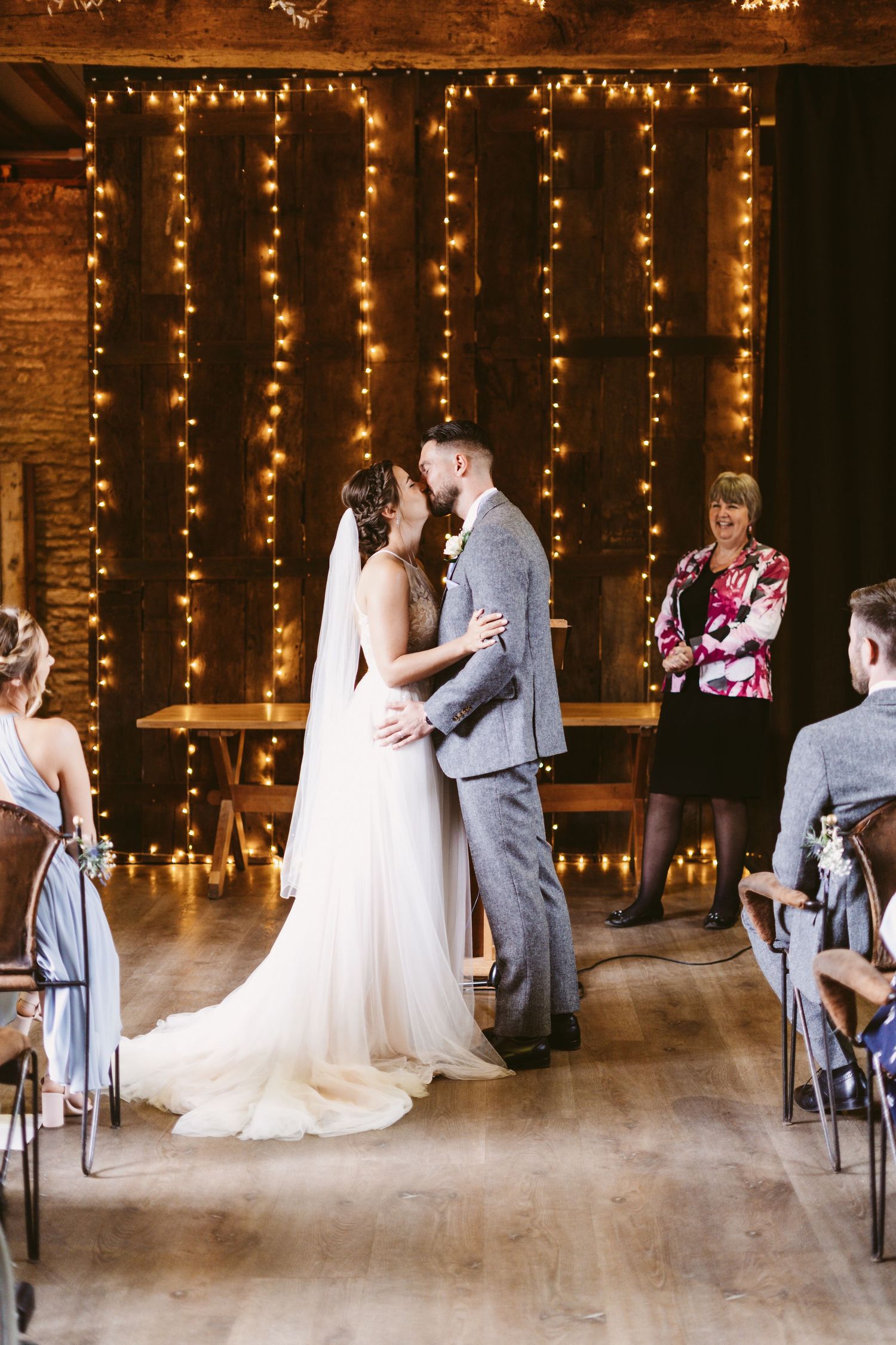 A romantic first dance moment in front of a fairy light backdrop at a rustic wedding venue.