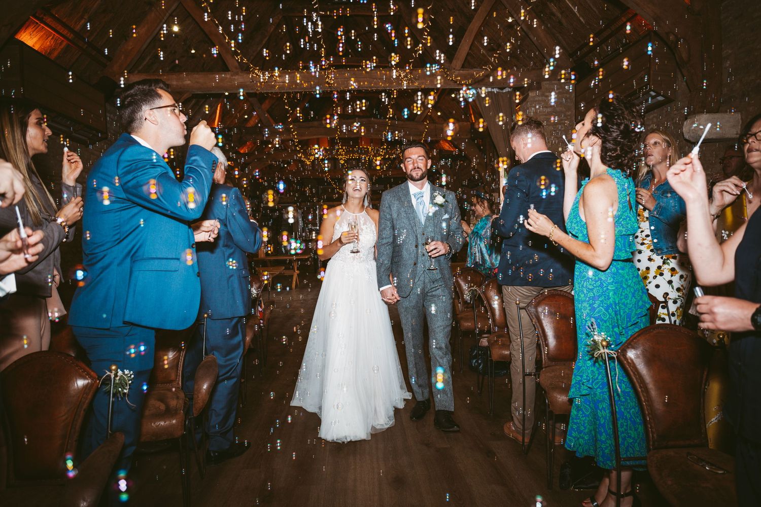 Wedding party celebrates with confetti and sparklers in a dimly lit rustic venue.