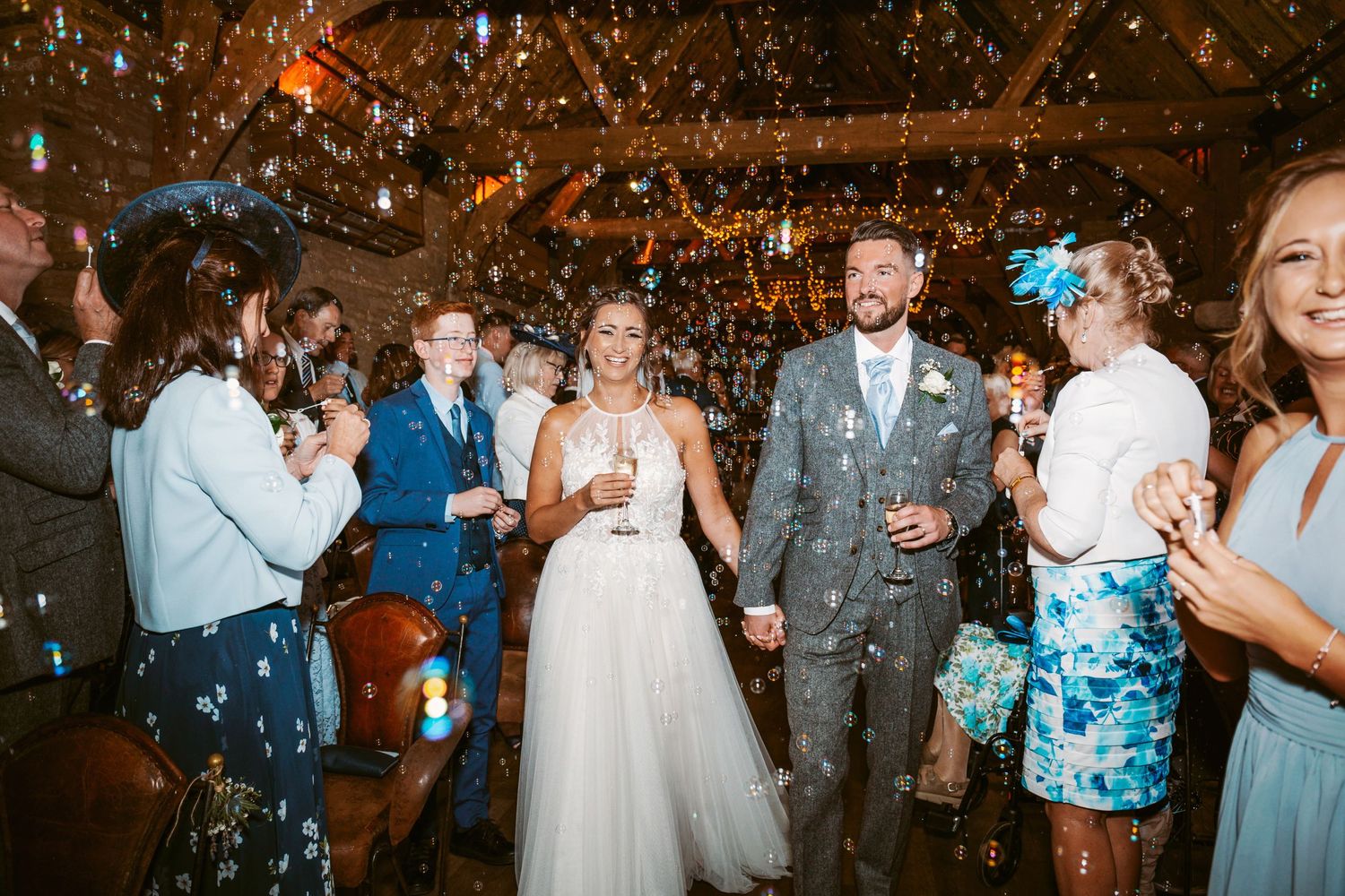 Wedding celebration with confetti shower in rustic venue with wooden beams and string lights.