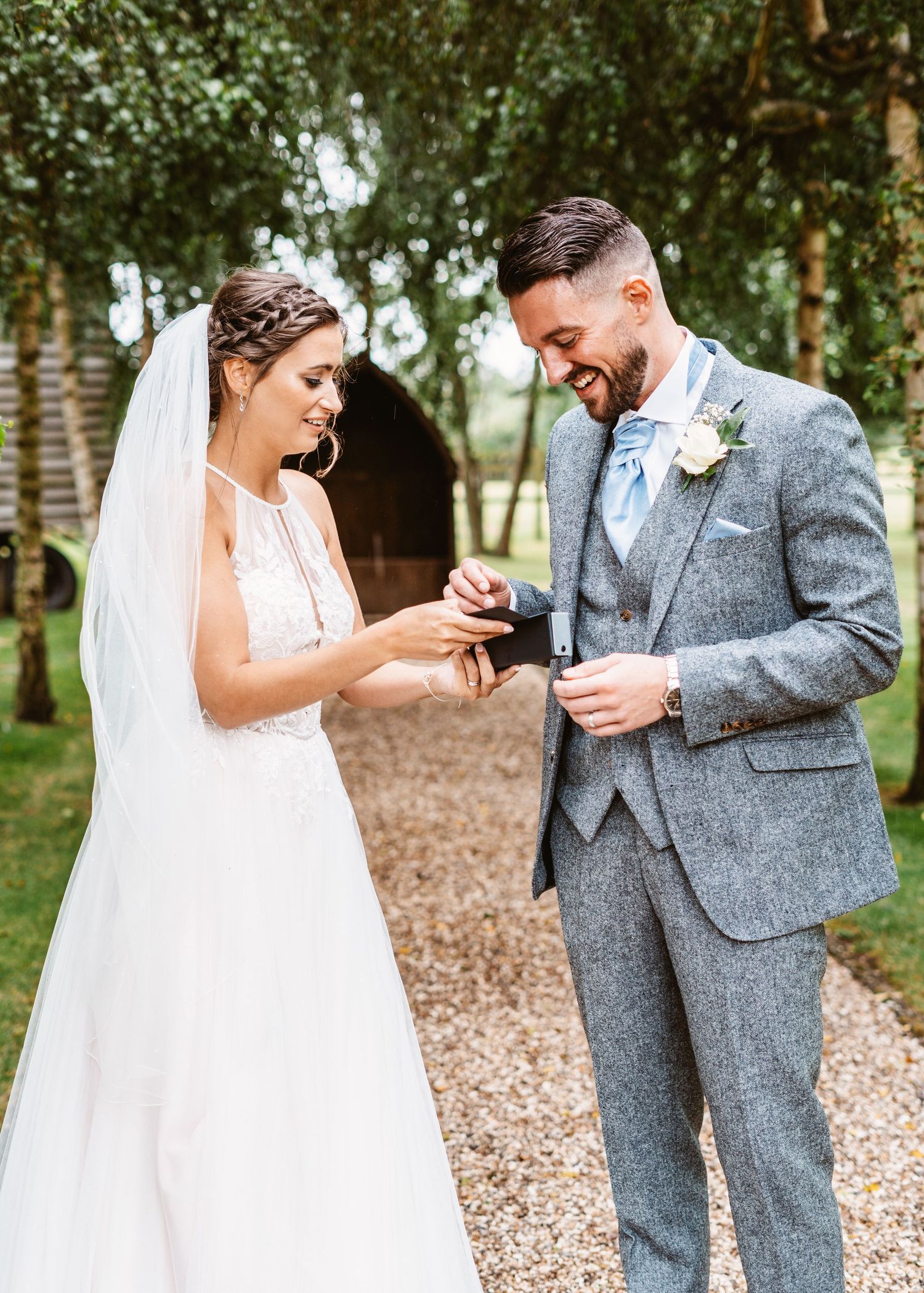 Couple laughs while exchanging rings on outdoor garden path.