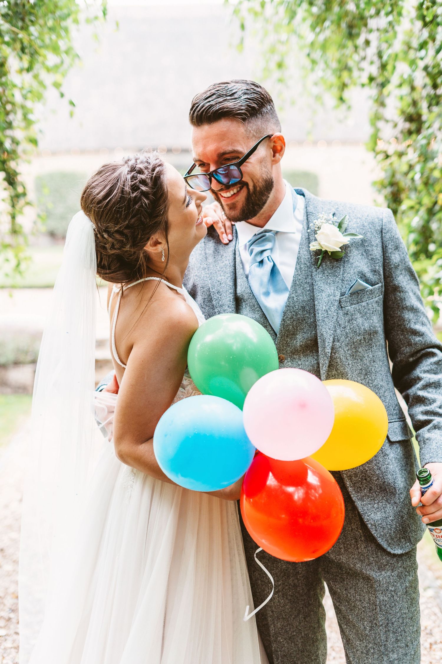 Happy couple shares a playful moment with colorful balloons during their wedding photoshoot.