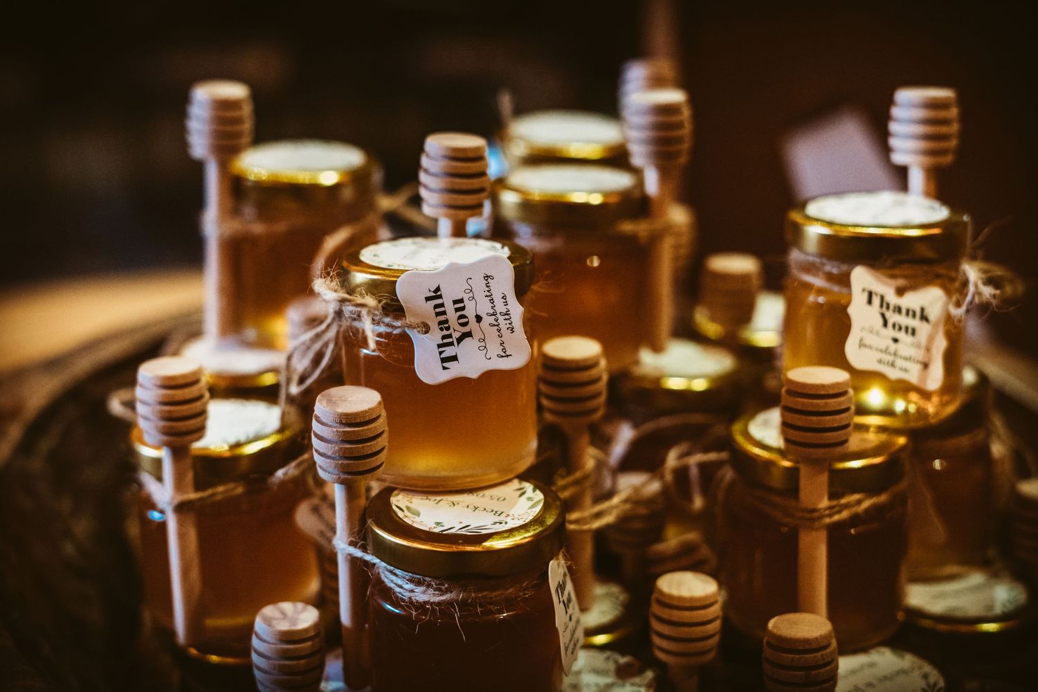 Small honey jars with wooden dippers arranged on dark wooden surface.